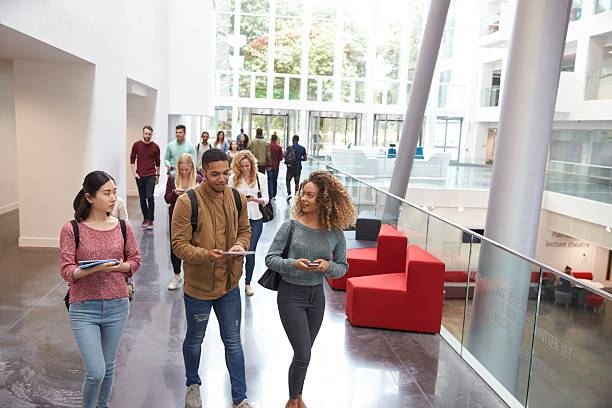 Group of UK university students walking and chatting in a bright campus atrium