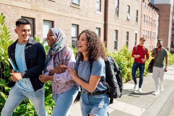 UK university students laughing together while walking near a campus building