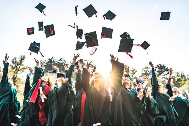 UK graduates throwing their caps in the air in celebration at sunset